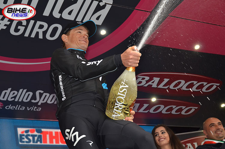 Vasil Kiryenka sul podio della 14a tappa da vincitore della cronometro Treviso/Valdobbiadene, stappa il prosecco italiano
